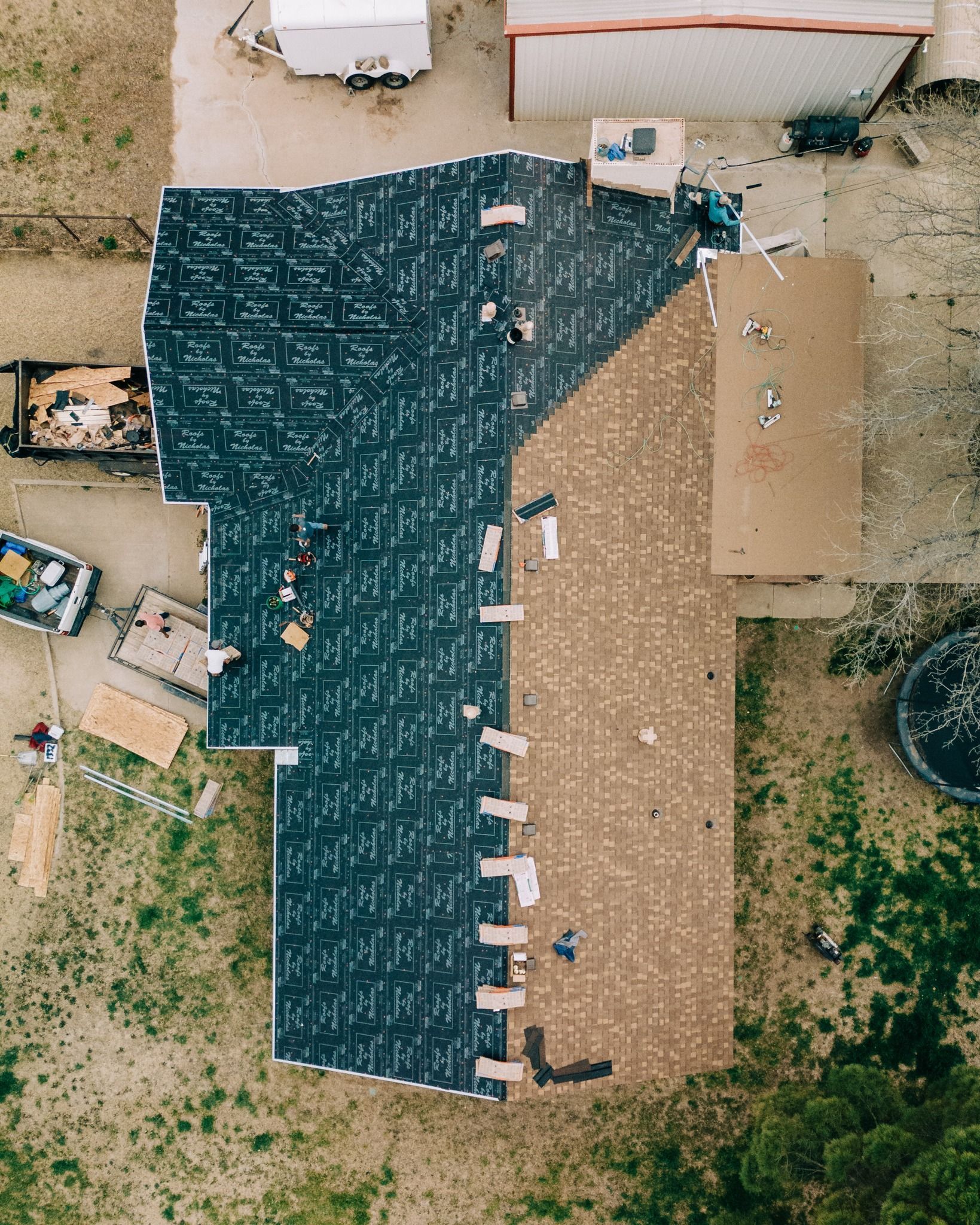 Aerial view of residential roof replacement showing underlayment installation and shingle removal in progress