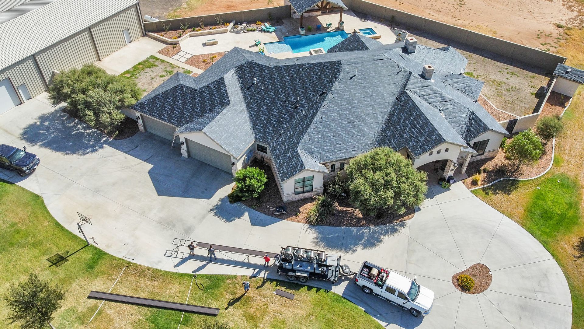 Aerial view of large home with new asphalt shingle roof and swimming pool in backyard