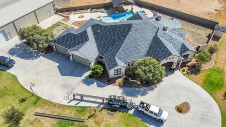 Aerial view of large home with new asphalt shingle roof and swimming pool in backyard