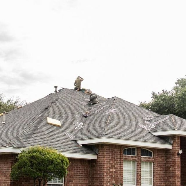 Roofer repairing damaged asphalt shingle roof on residential home