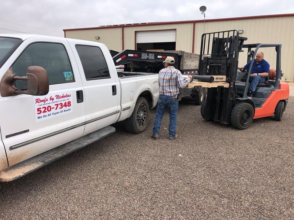 Roofs by Nicholas team loading roofing materials with forklift into company truck