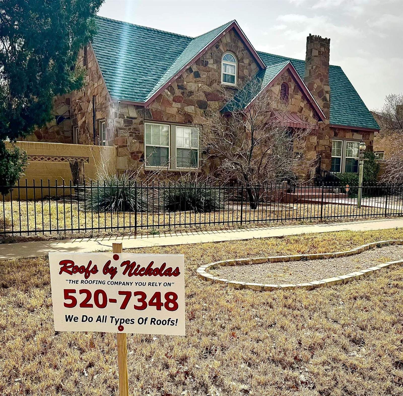 Roofs by Nicholas yard sign in front of a stone home with a new shingle roof