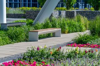 A bench is sitting in the middle of a garden surrounded by flowers.