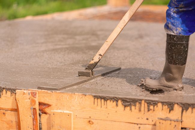 a person with a shovel and a spatula on a concrete slab