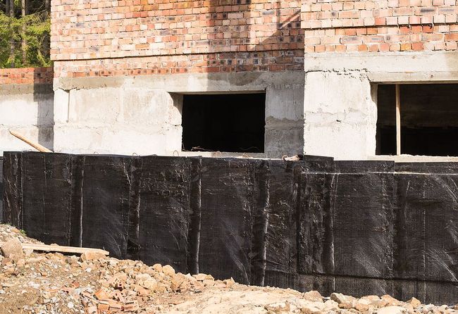 a building under construction with a brick wall and two windows