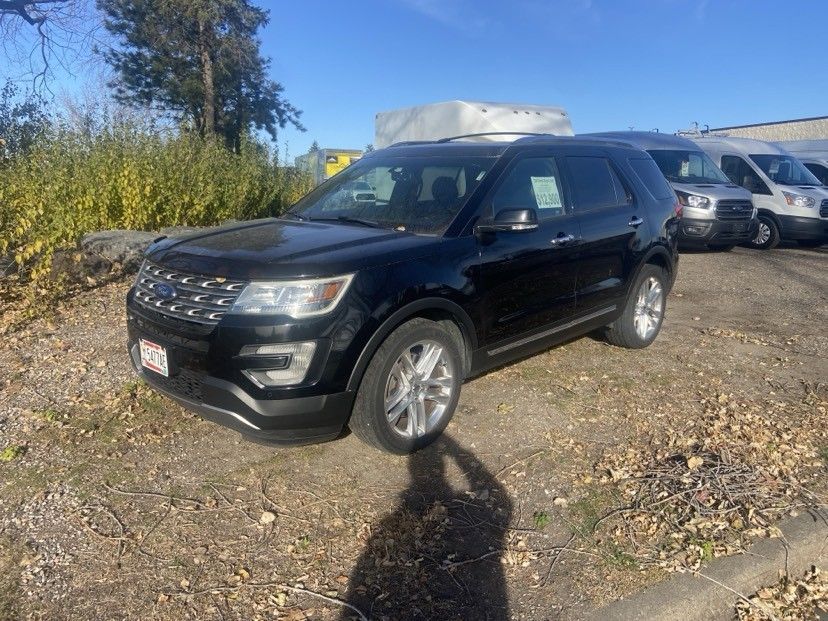 Black Ford Explorer SUV parked outdoors on a sunny day. Other vans visible in the background.