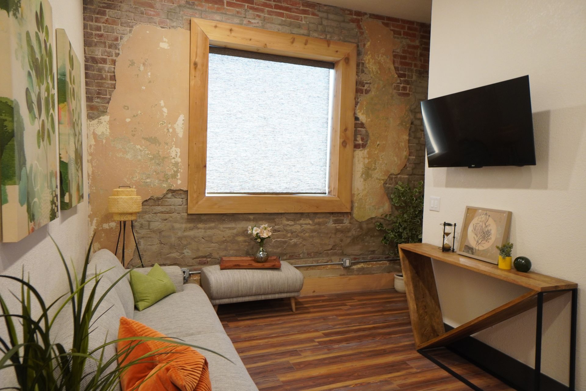 Living room with exposed brick wall, sofa, wood window frame, TV, and console table.