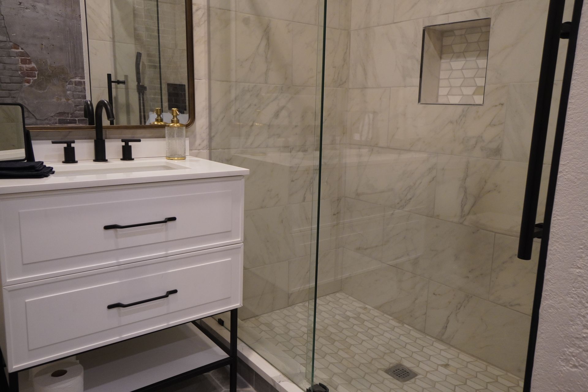 White bathroom vanity and shower with marble tile walls.