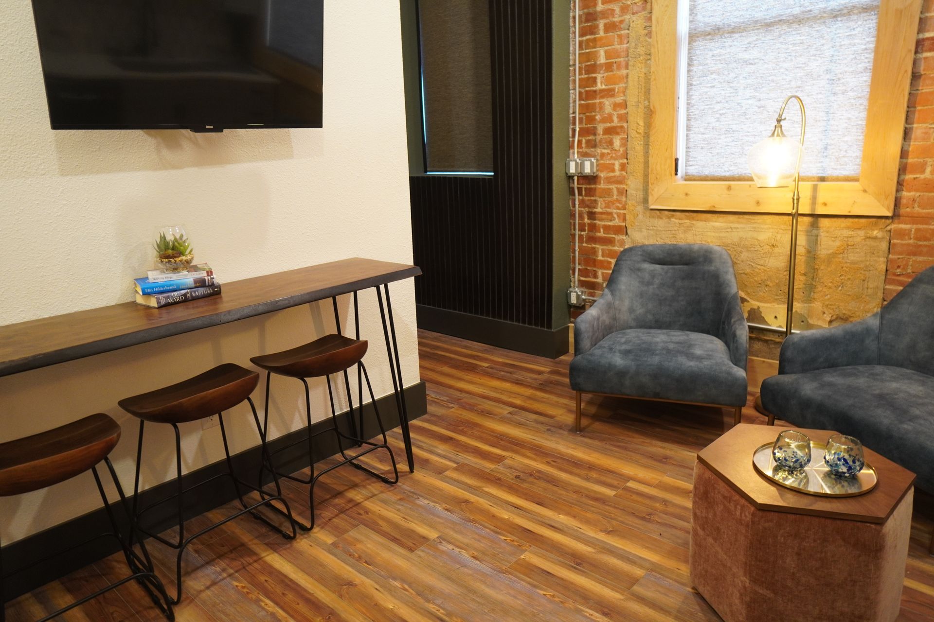 A modern lounge area with seating, a high table, and a TV mounted on the wall.