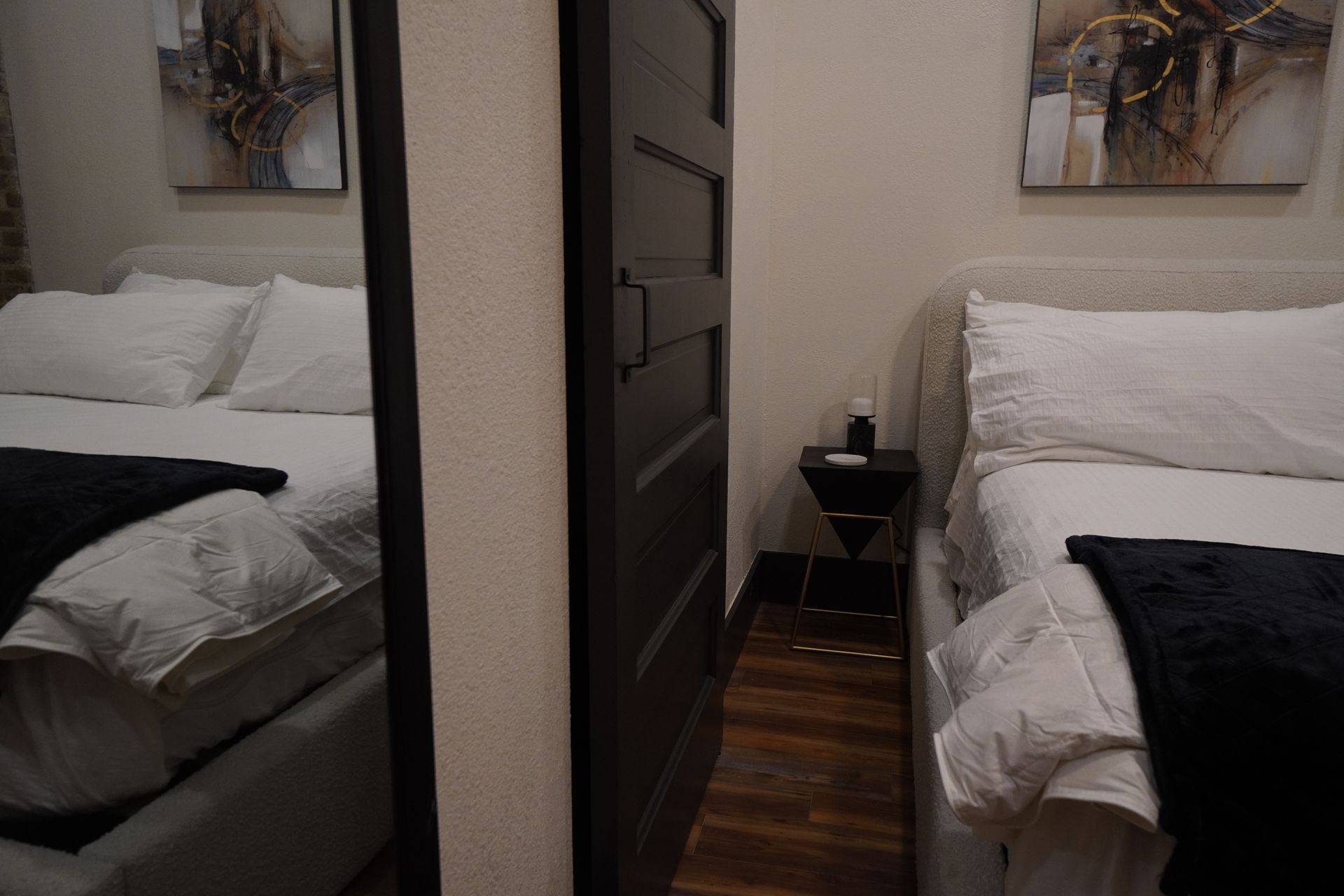 A bedroom with two beds, a black door, and art on the walls.