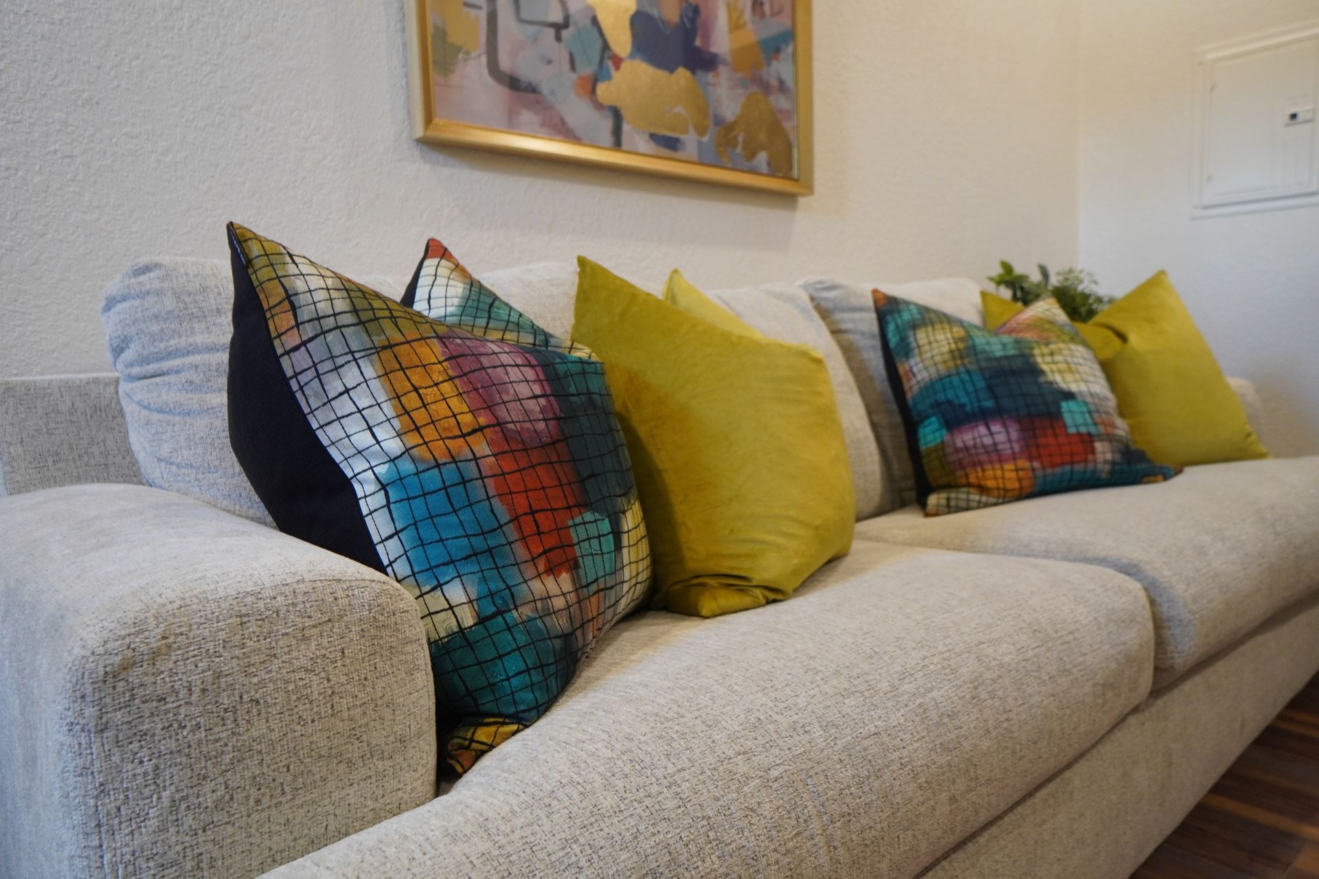 Beige couch with colorful throw pillows, and art on the wall.