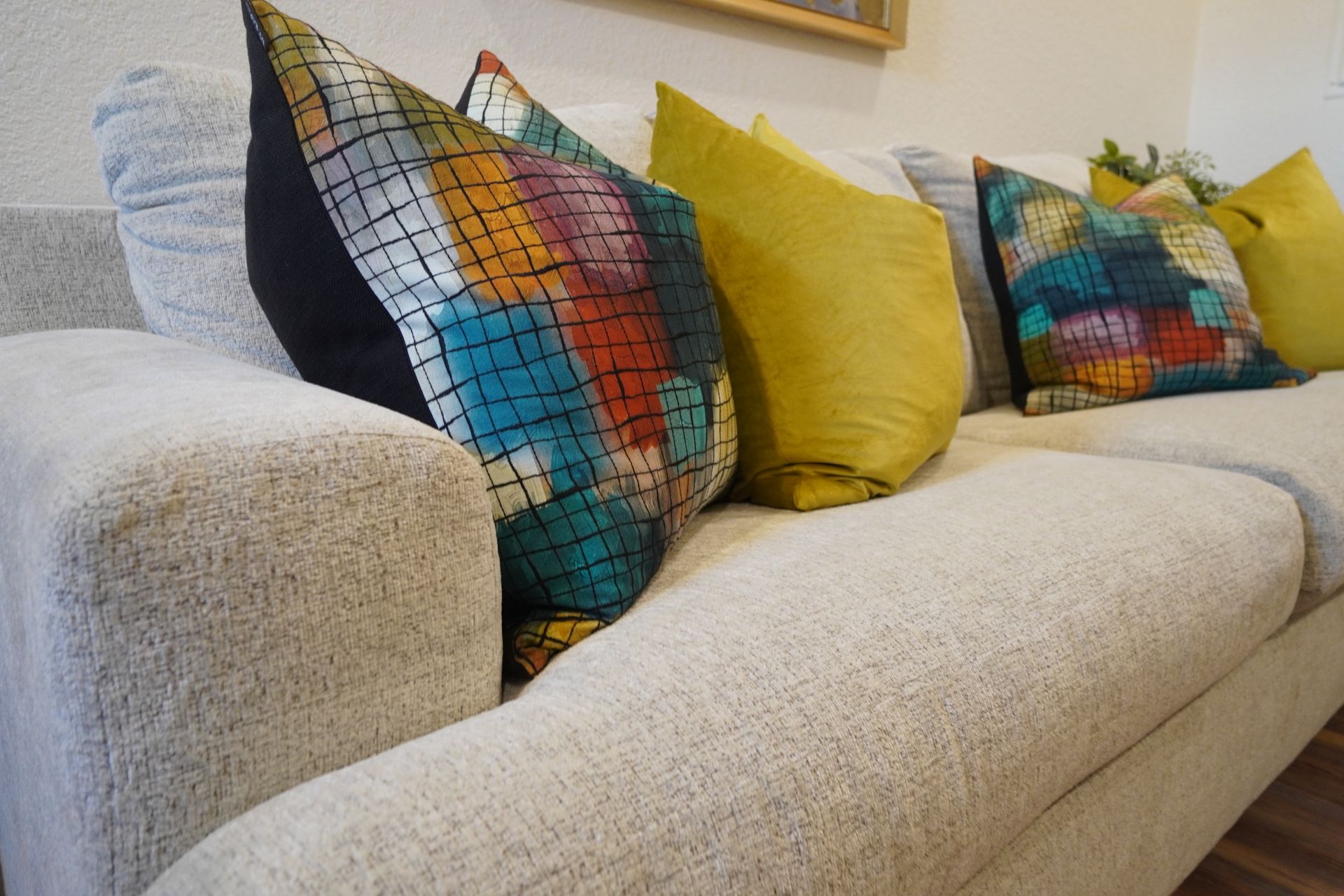 Beige couch with colorful throw pillows, including teal, yellow, and abstract patterned designs.