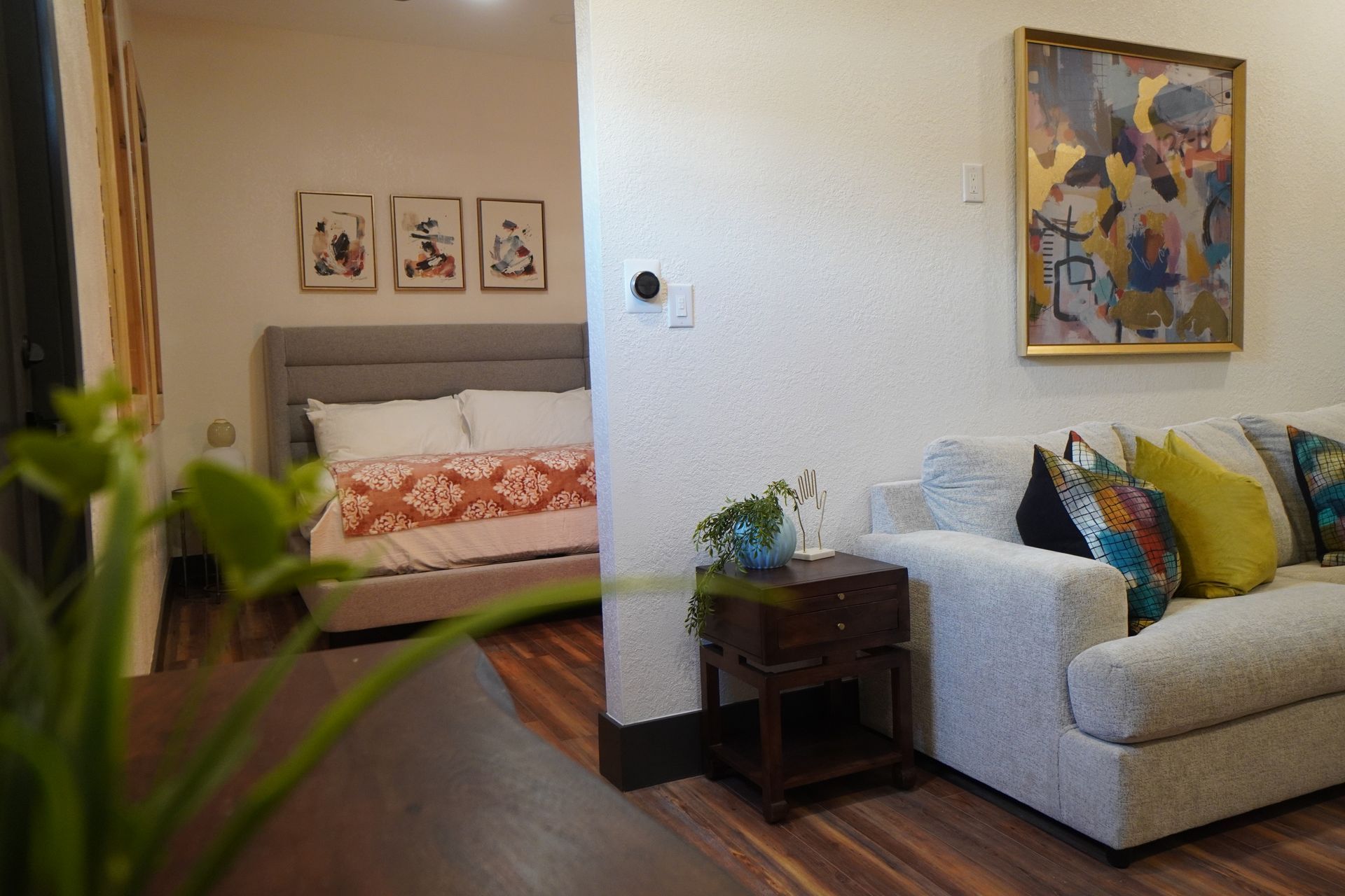 Bedroom with bed, art, and sofa; warm tones, open concept, contemporary decor.