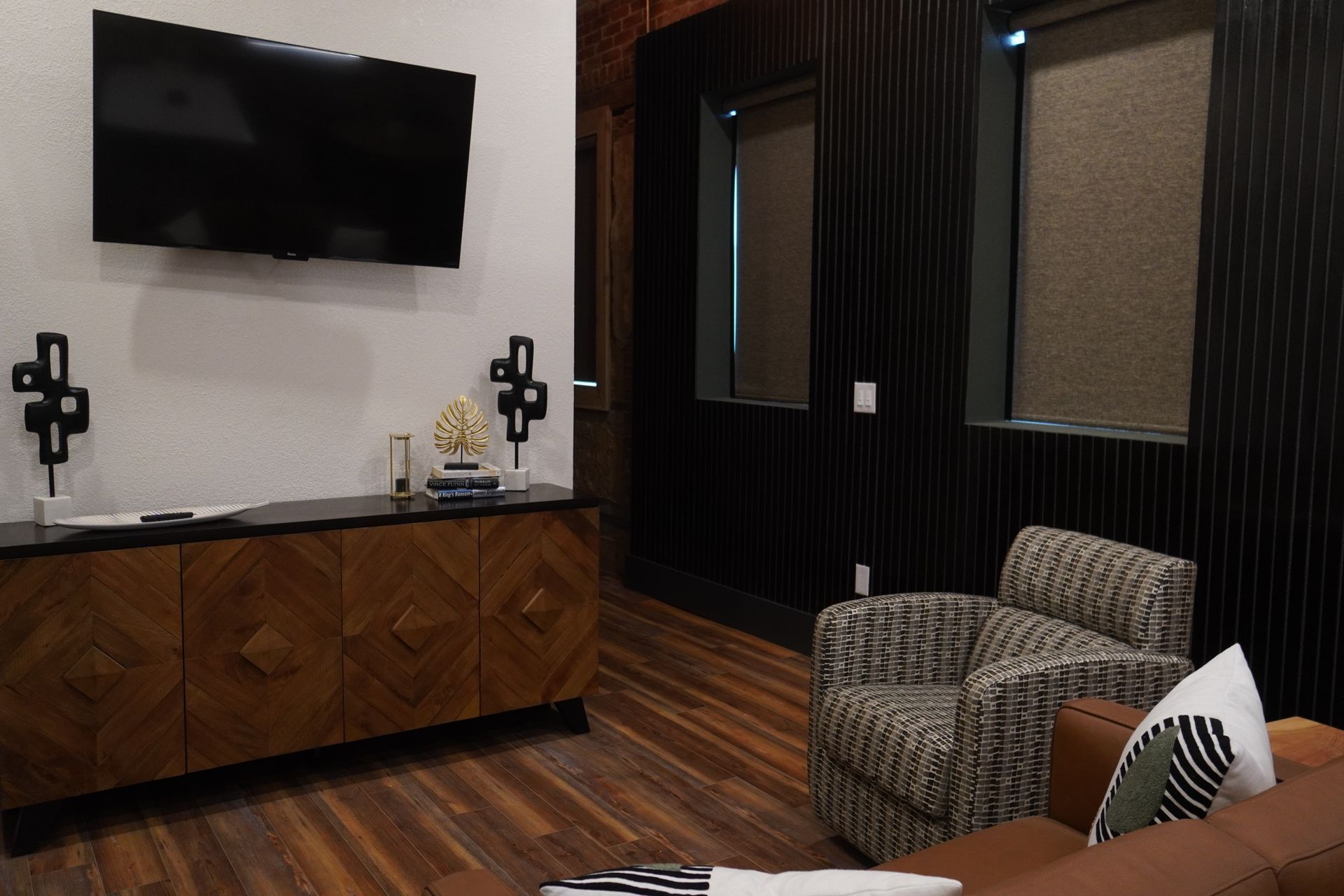 Living room with TV, dark wood cabinet, arm chair, and wood accent wall.