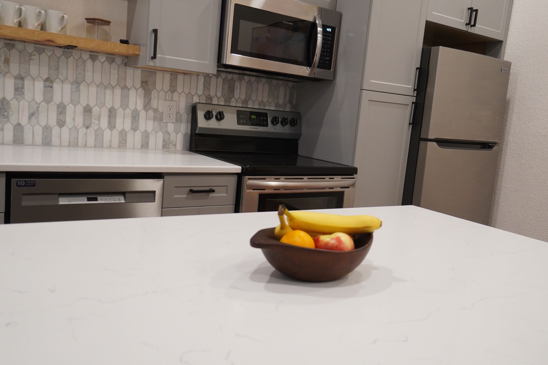 Kitchen with white countertops, stainless steel appliances, and a fruit bowl.