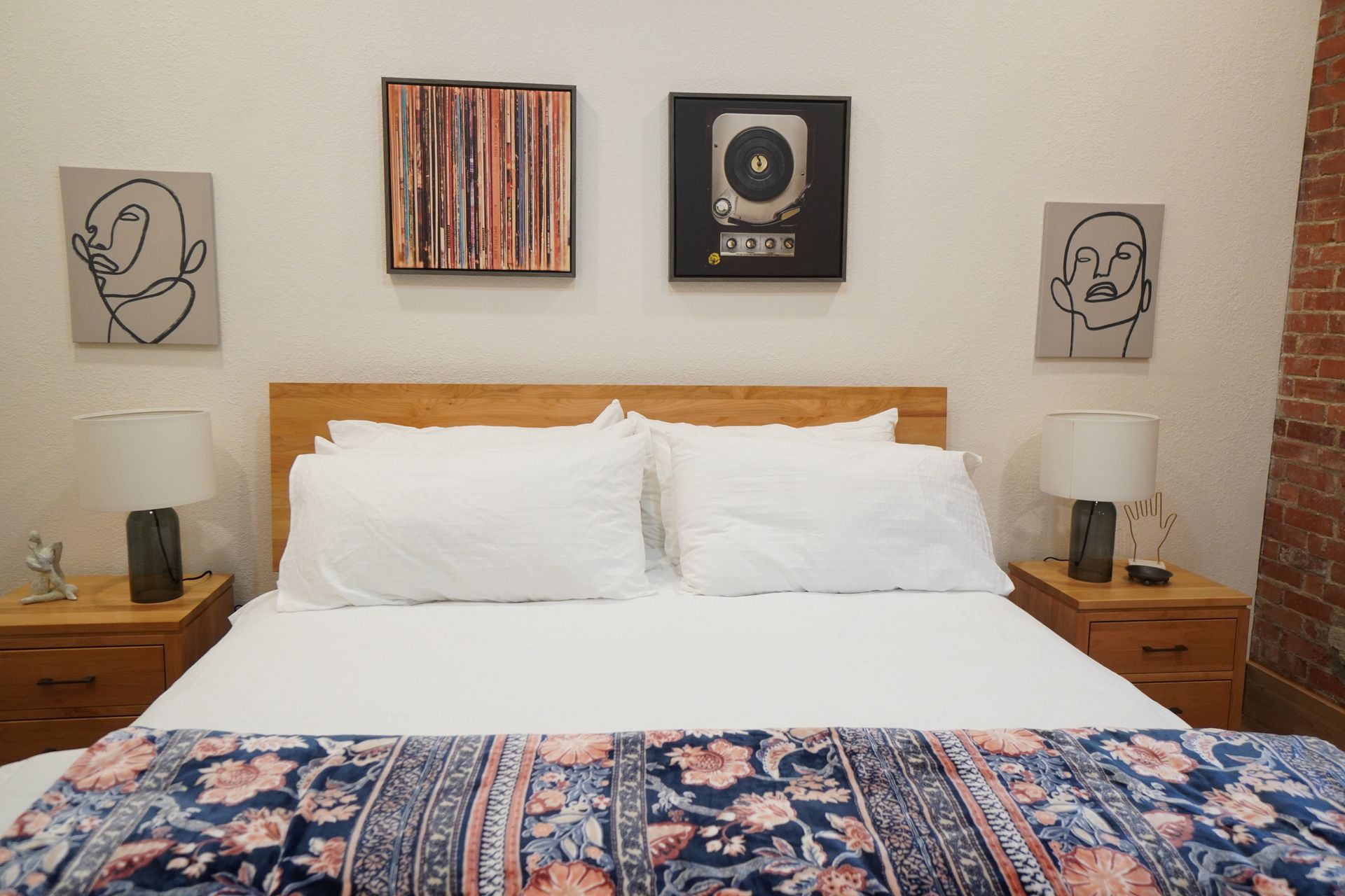 Bedroom with a wooden headboard, white bedding, and artwork above the bed.