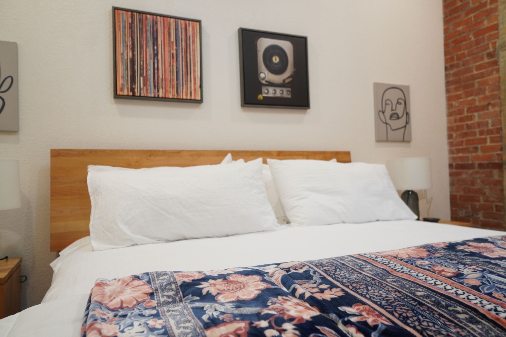 Bedroom with a bed, artwork, and exposed brick wall.