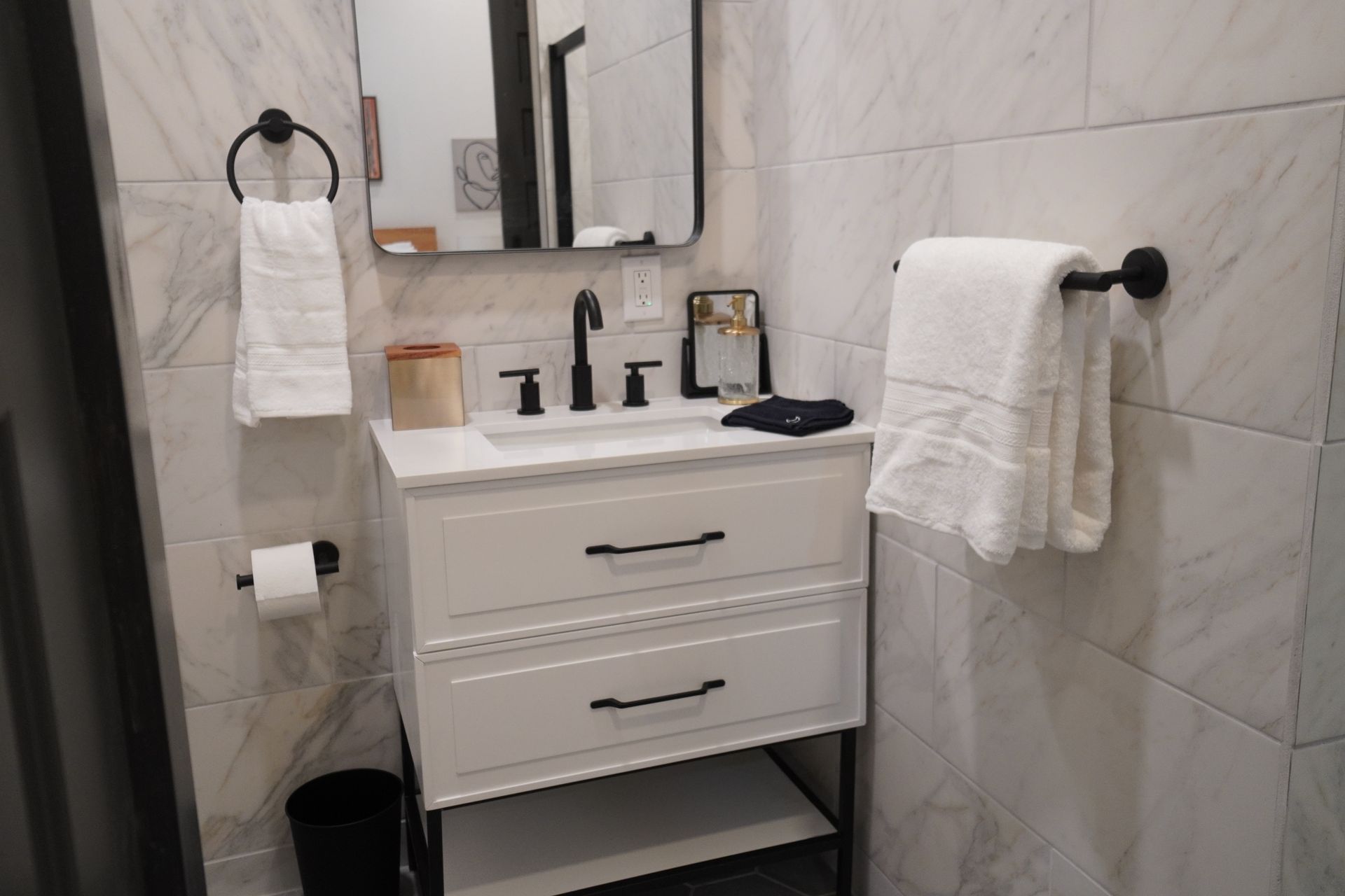 White bathroom with a vanity, mirror, and white towels.