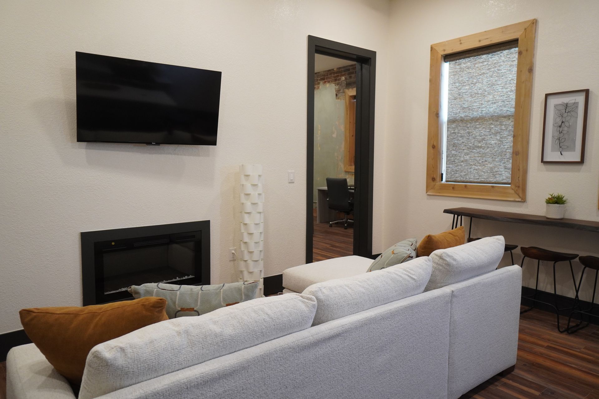 Living room with white sofa, TV, fireplace, wooden table, and doorway.