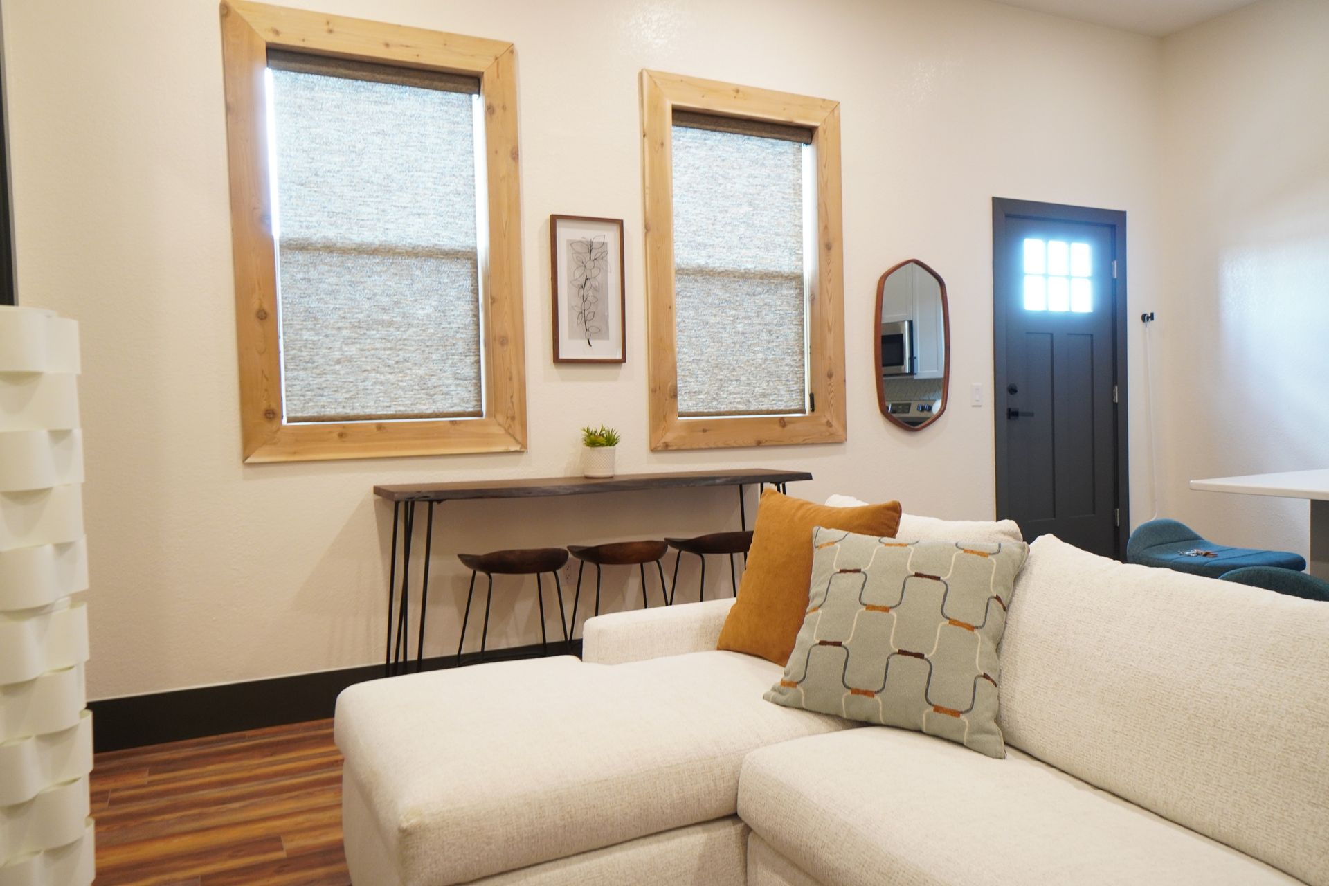 Living room with white sectional sofa, two windows with blinds, wood trim, and a console table.