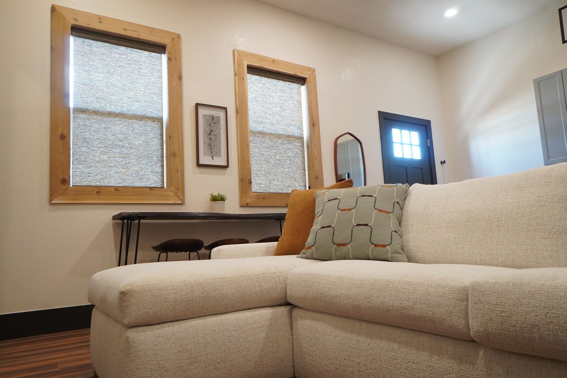 Living room with sectional sofa, two windows, and dark door.