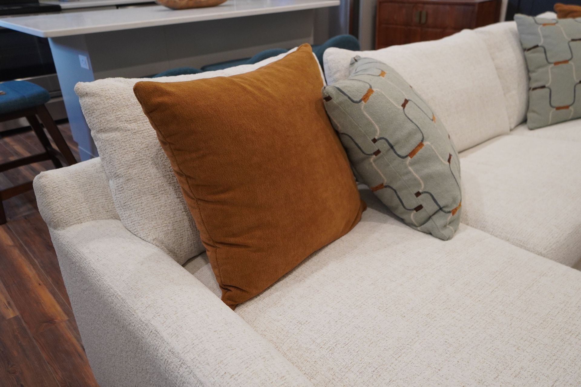 Cream-colored sectional sofa with orange, patterned, and white pillows.