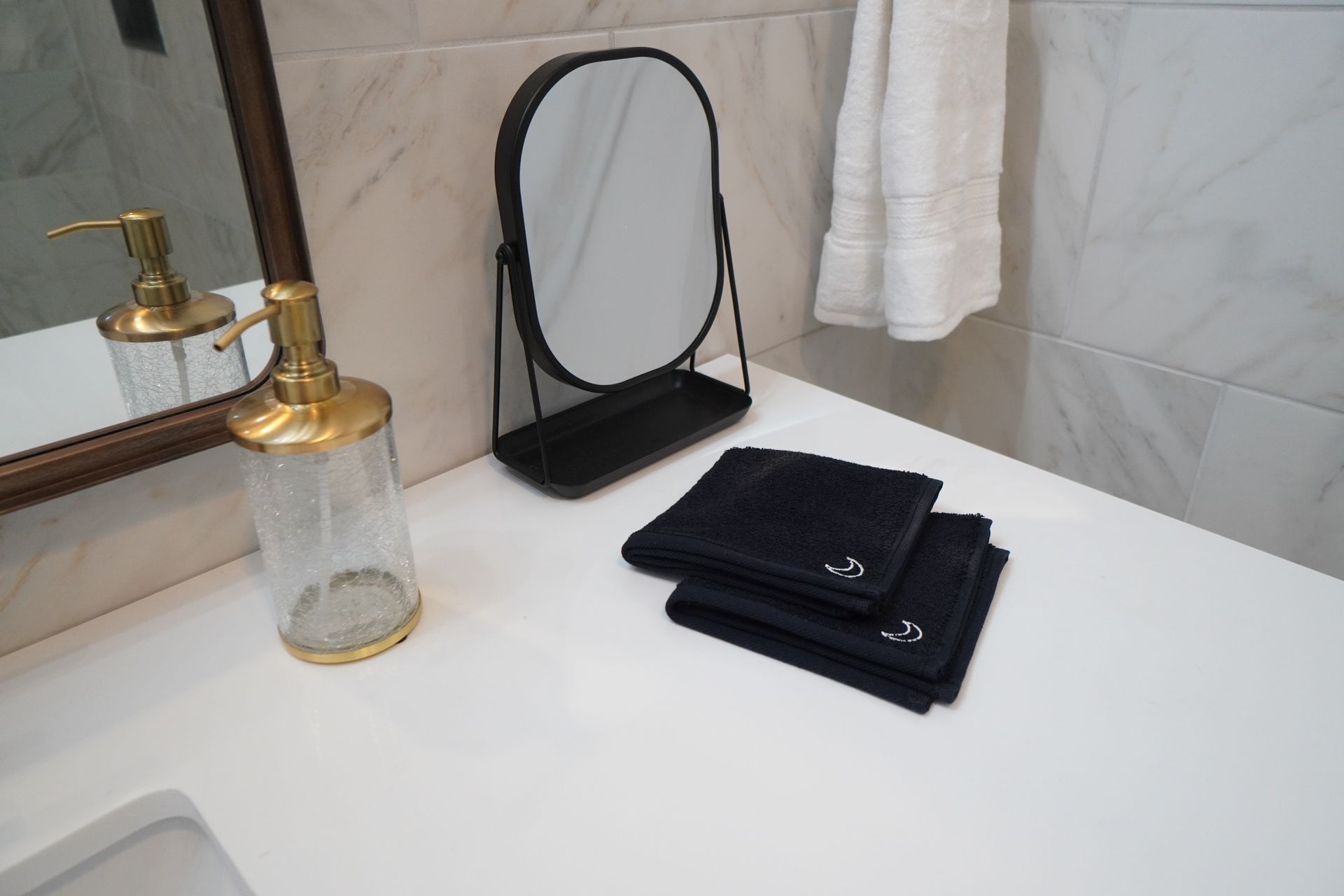 Bathroom countertop with black towels, a mirror, and a soap dispenser.