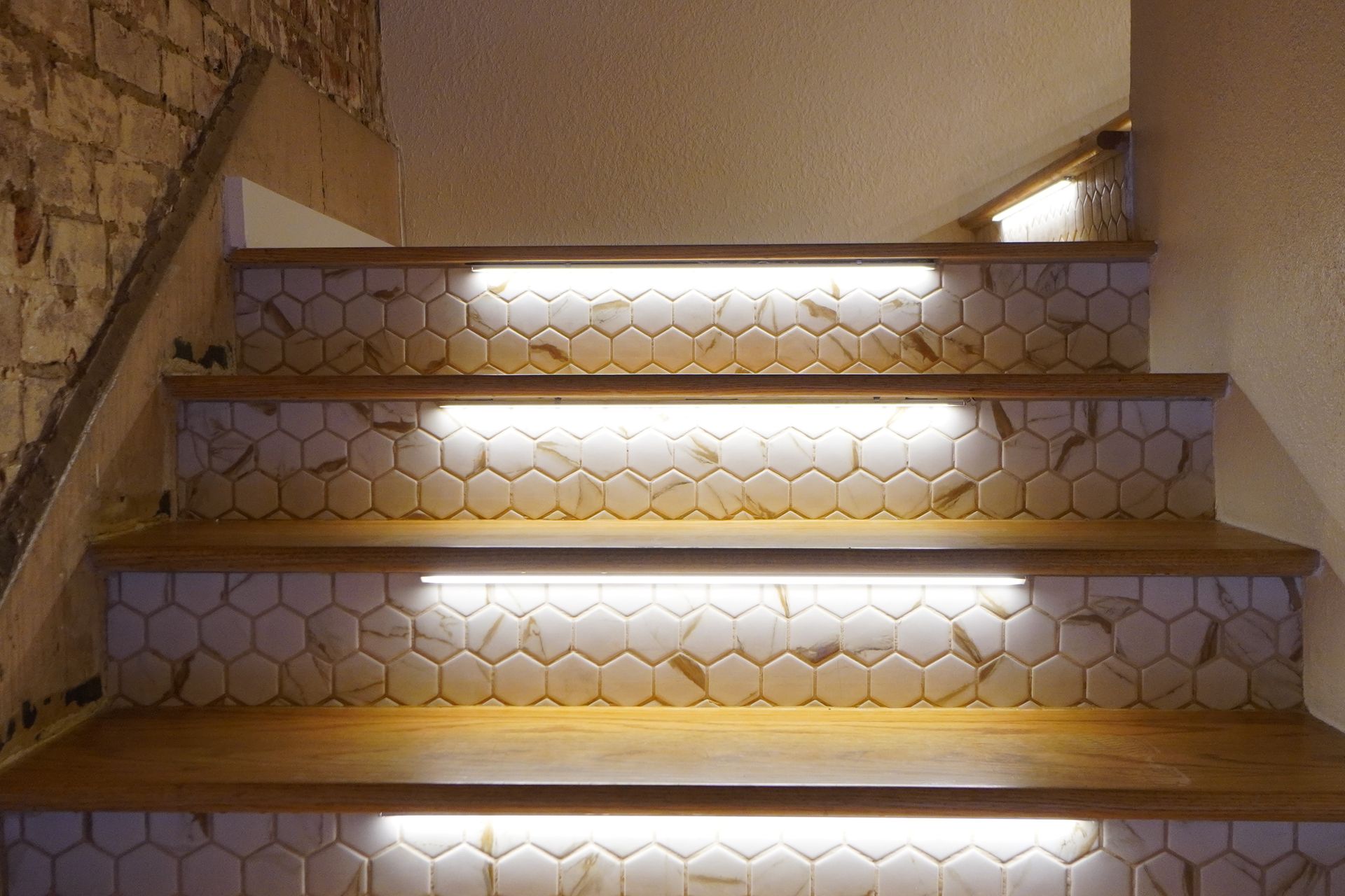 Wooden staircase with honeycomb tile risers, illuminated by LED lights.