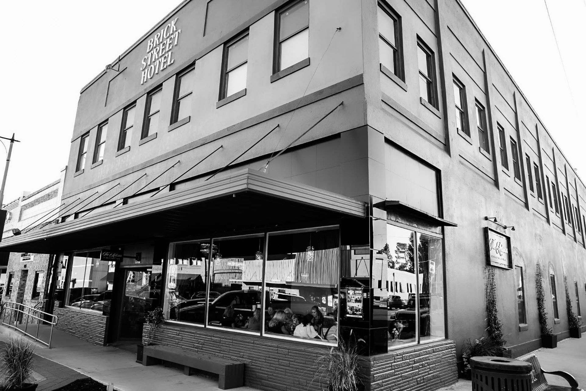 Black and white photo of a three-story brick building with a restaurant on the ground floor.