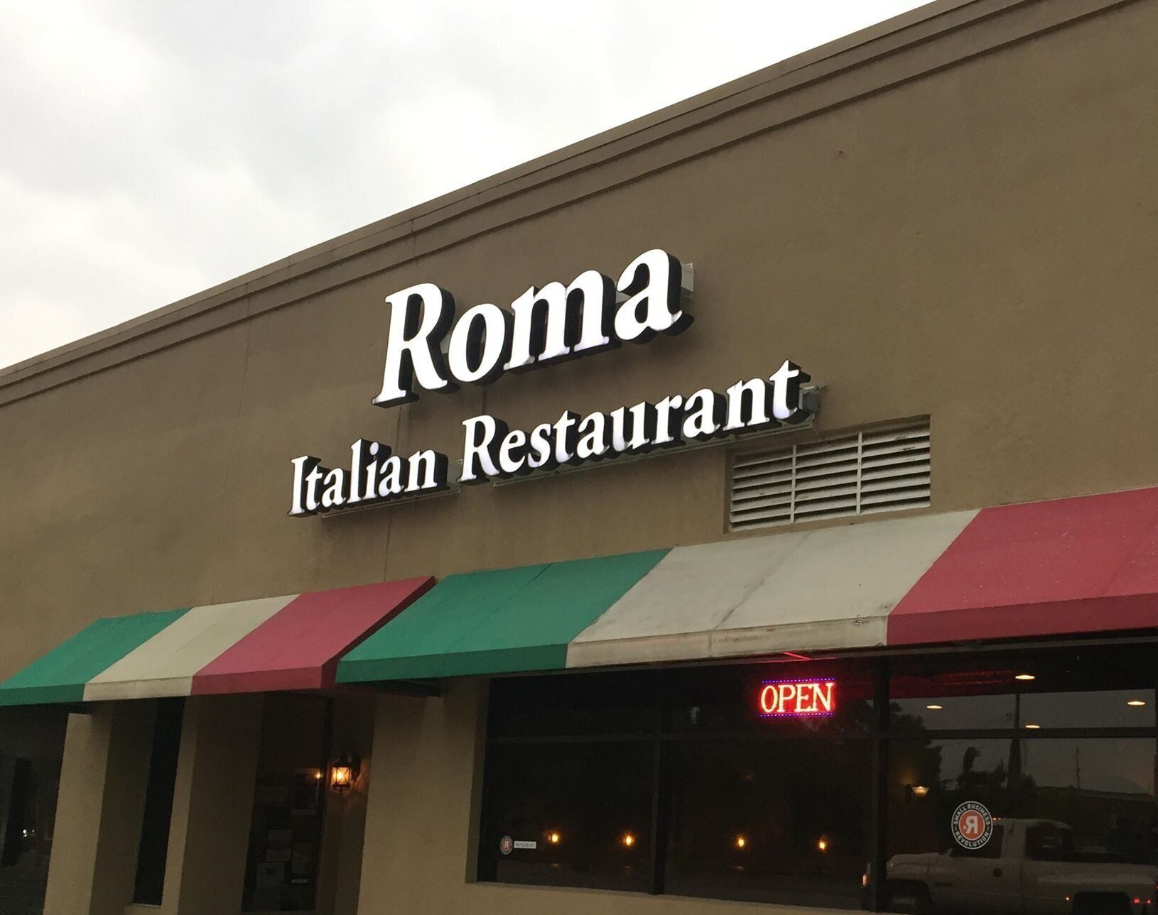 Roma Italian Restaurant storefront with awning, sign, and "Open" neon sign.
