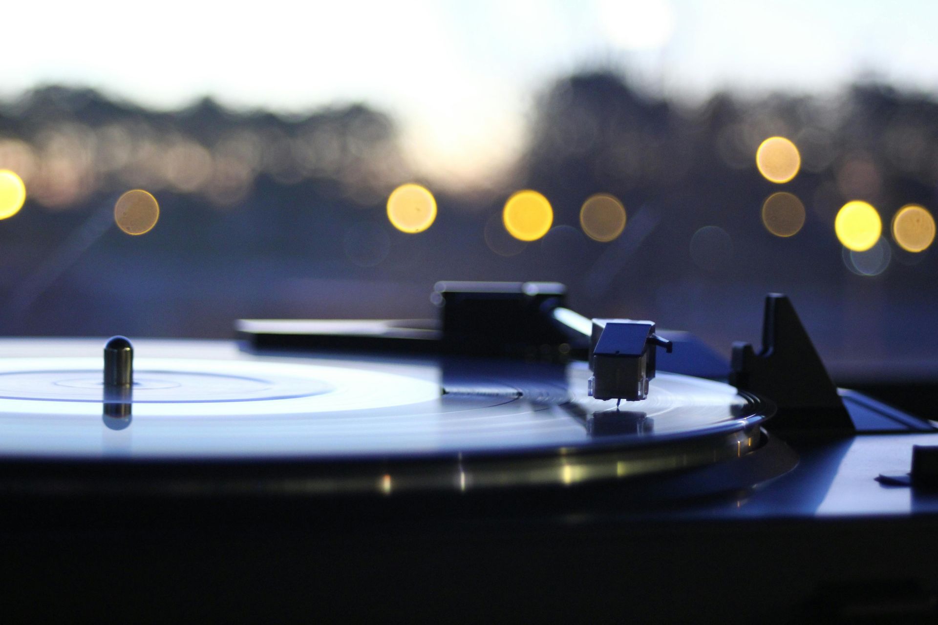 Vinyl record spinning on a turntable with blurred city lights in the background
