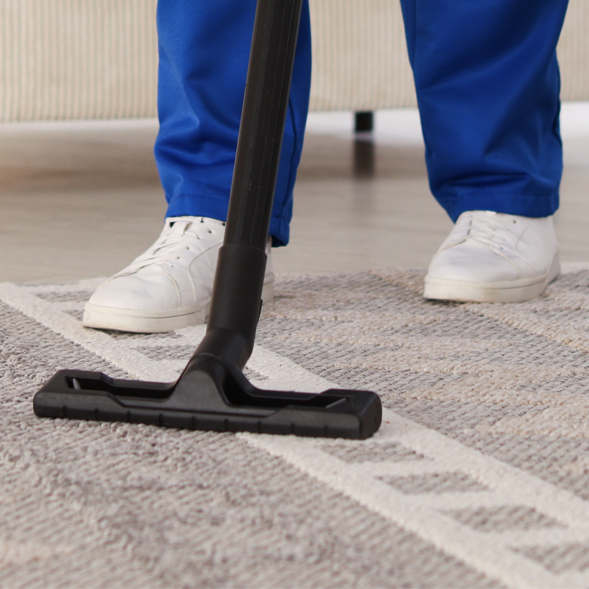 Eco Friend Carpet Clean - Person in blue cleaning with a vacuum cleaner on a carpet.