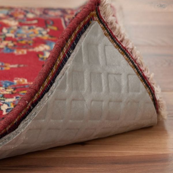 Eco Friend Carpet Clean - Red rug with fringe, showing underside with non-slip pad on wooden floor.