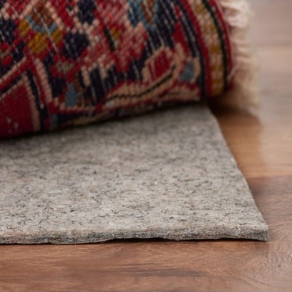 Eco Friend Carpet Clean - Rolled rug on top of a gray rug pad, set on a wood floor.