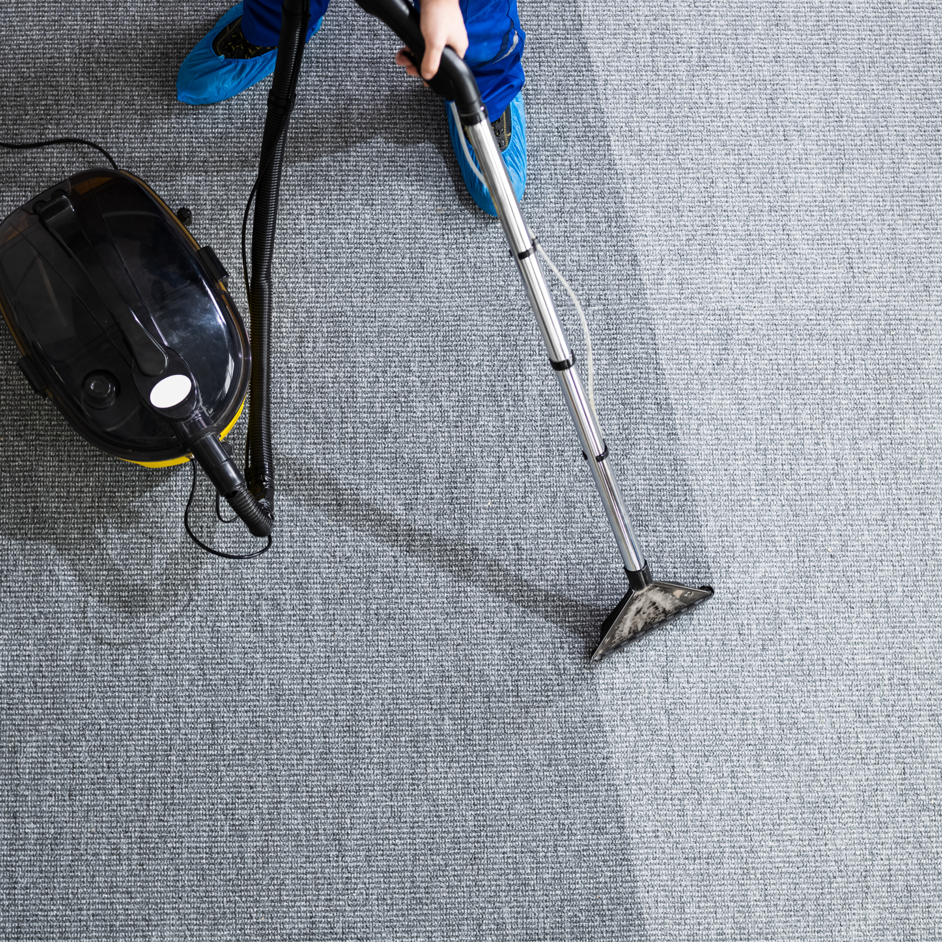Eco Friend Carpet Clean - Person vacuuming a gray carpet; the clean side is noticeably lighter than the dirty side.