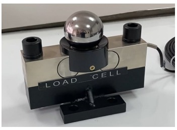Una bola de metal brillante se encuentra encima de una celda de carga,