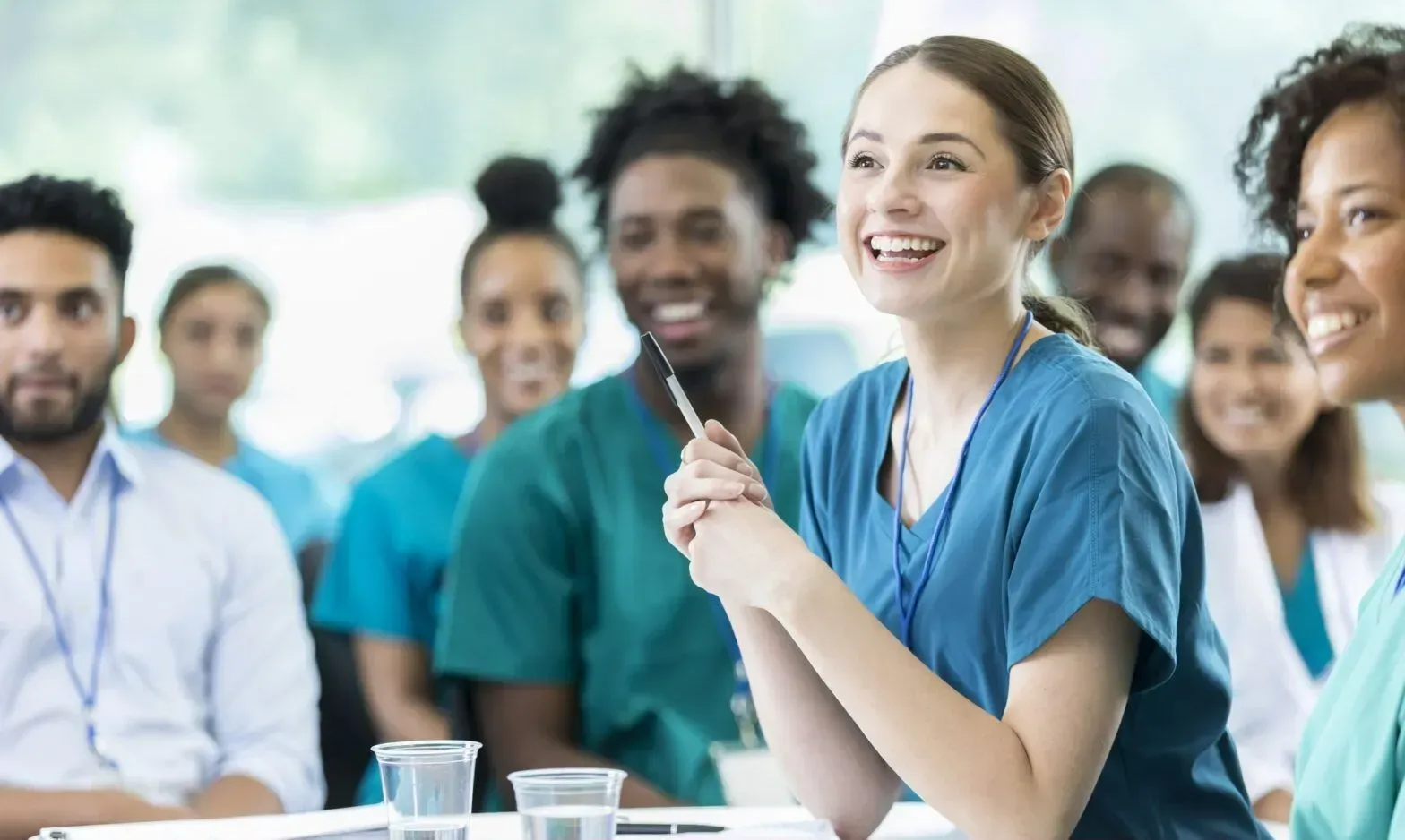 A group of nurses are sitting at a table having a meeting.