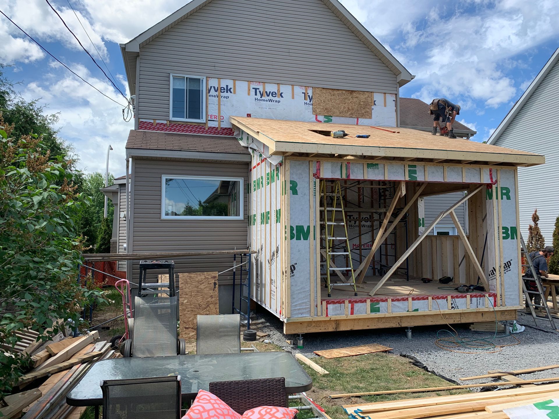 Maison en construction avec une nouvelle extension. Charpente et bardage en bois visibles.
