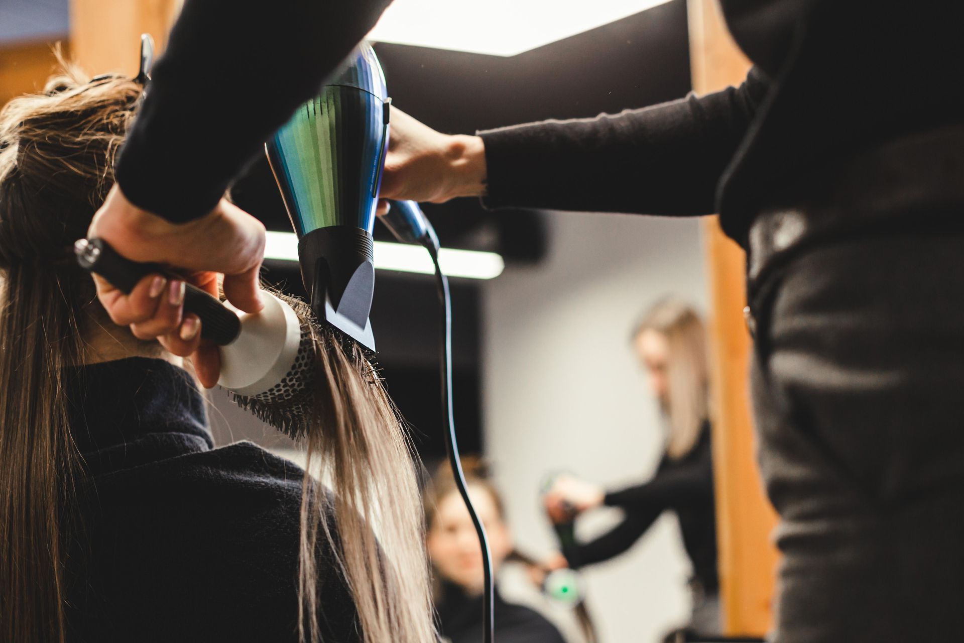 a woman is getting her hair blow dried by a hairdresser in a salon .