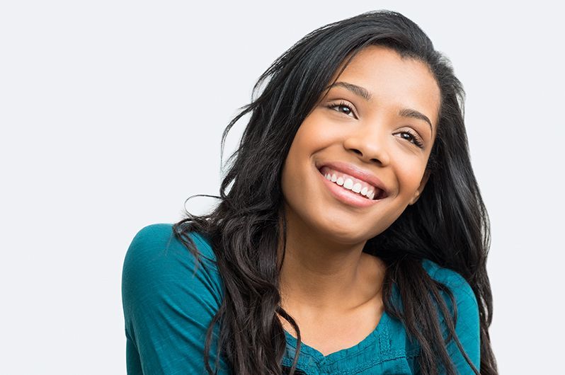 a woman in a blue shirt is smiling and looking at the camera .