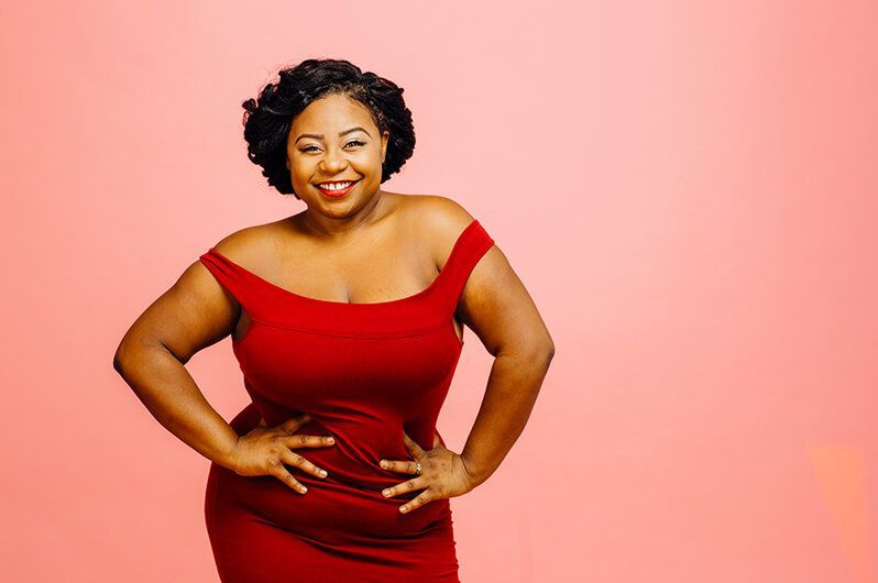 a woman in a red dress is standing with her hands on her hips .