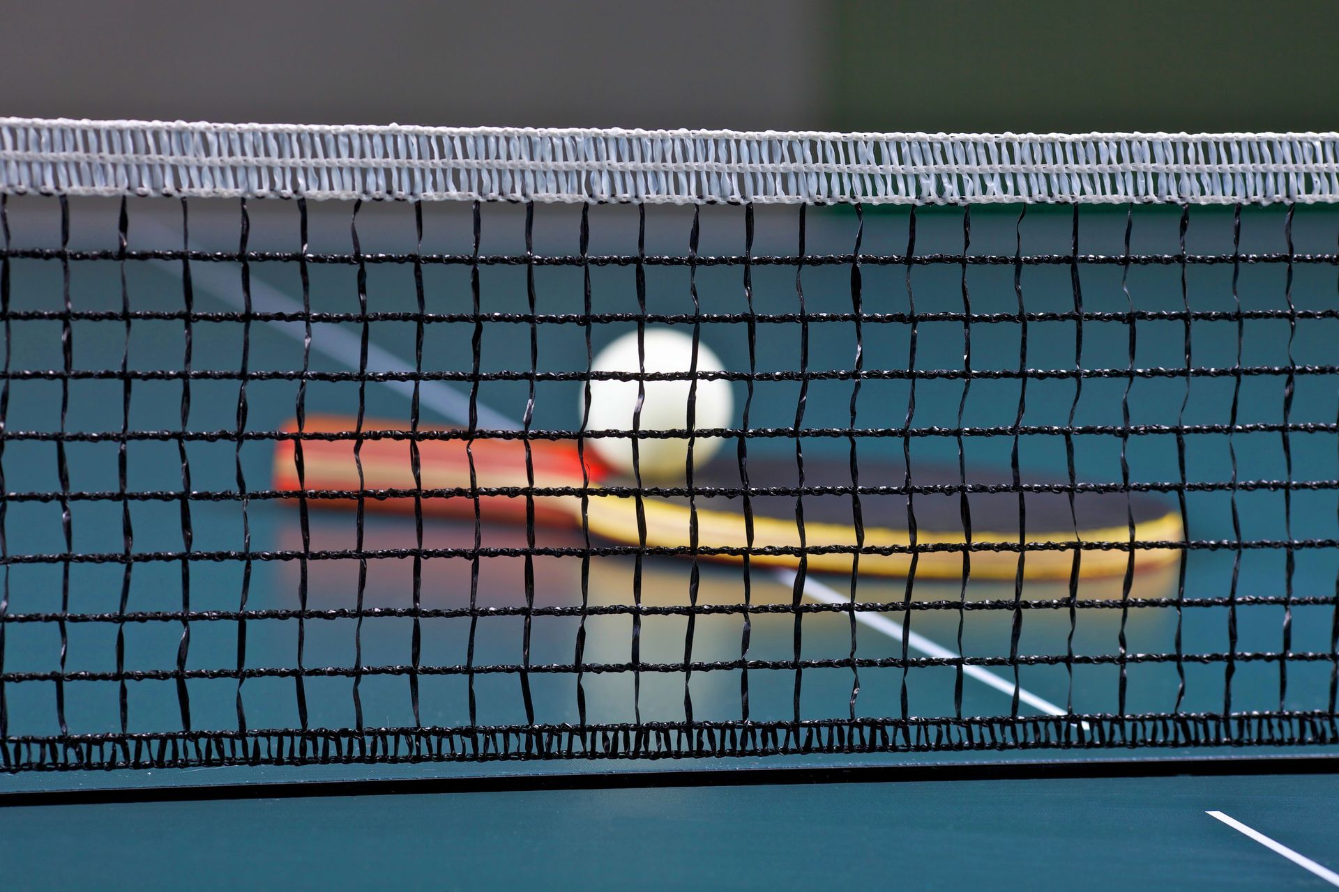 Ein Tennisnetz mit einem Ball und einem Schläger dahinter