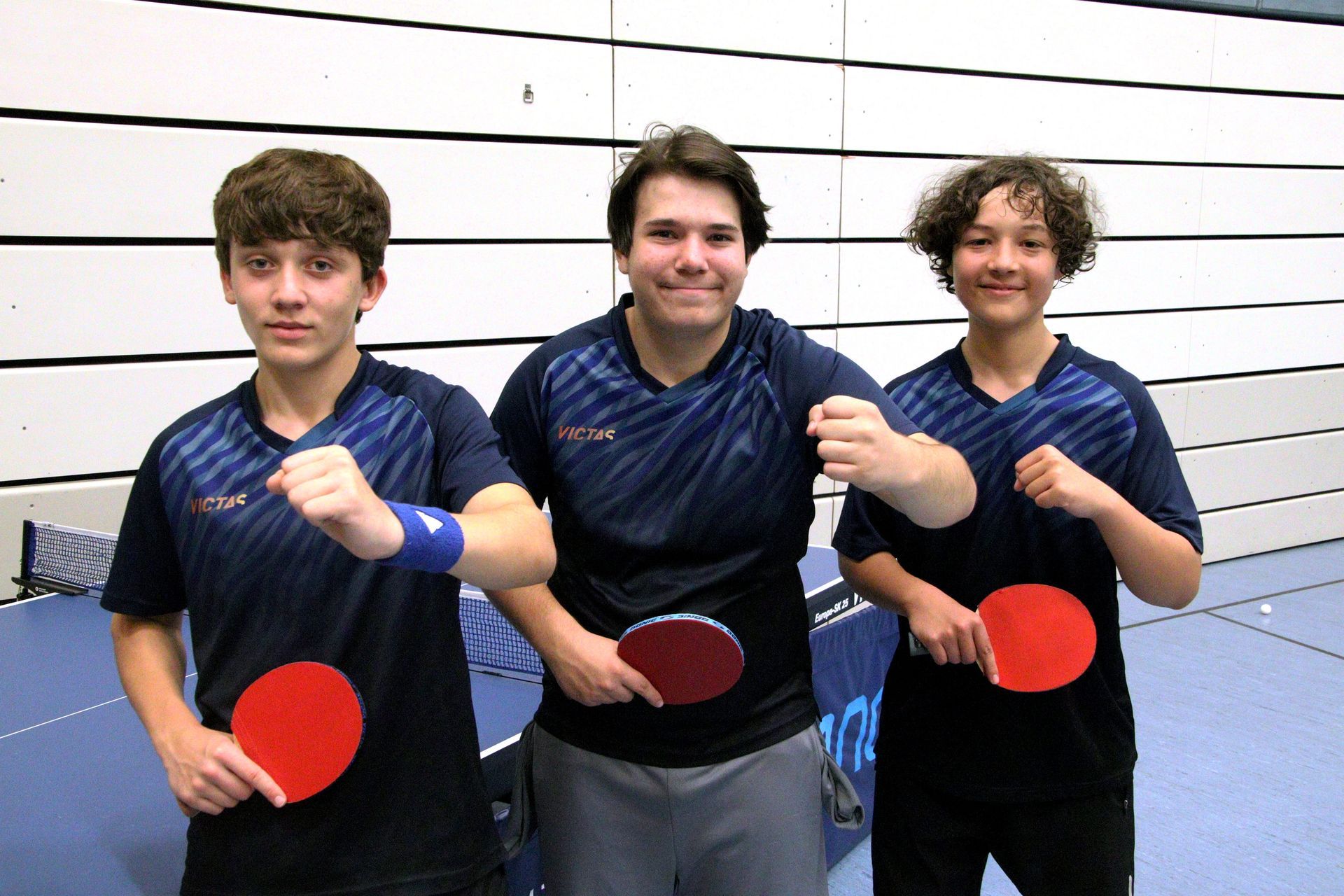 Eine Gruppe junger Jungen sitzt mit Ping-Pong-Schlägern an einem Tisch