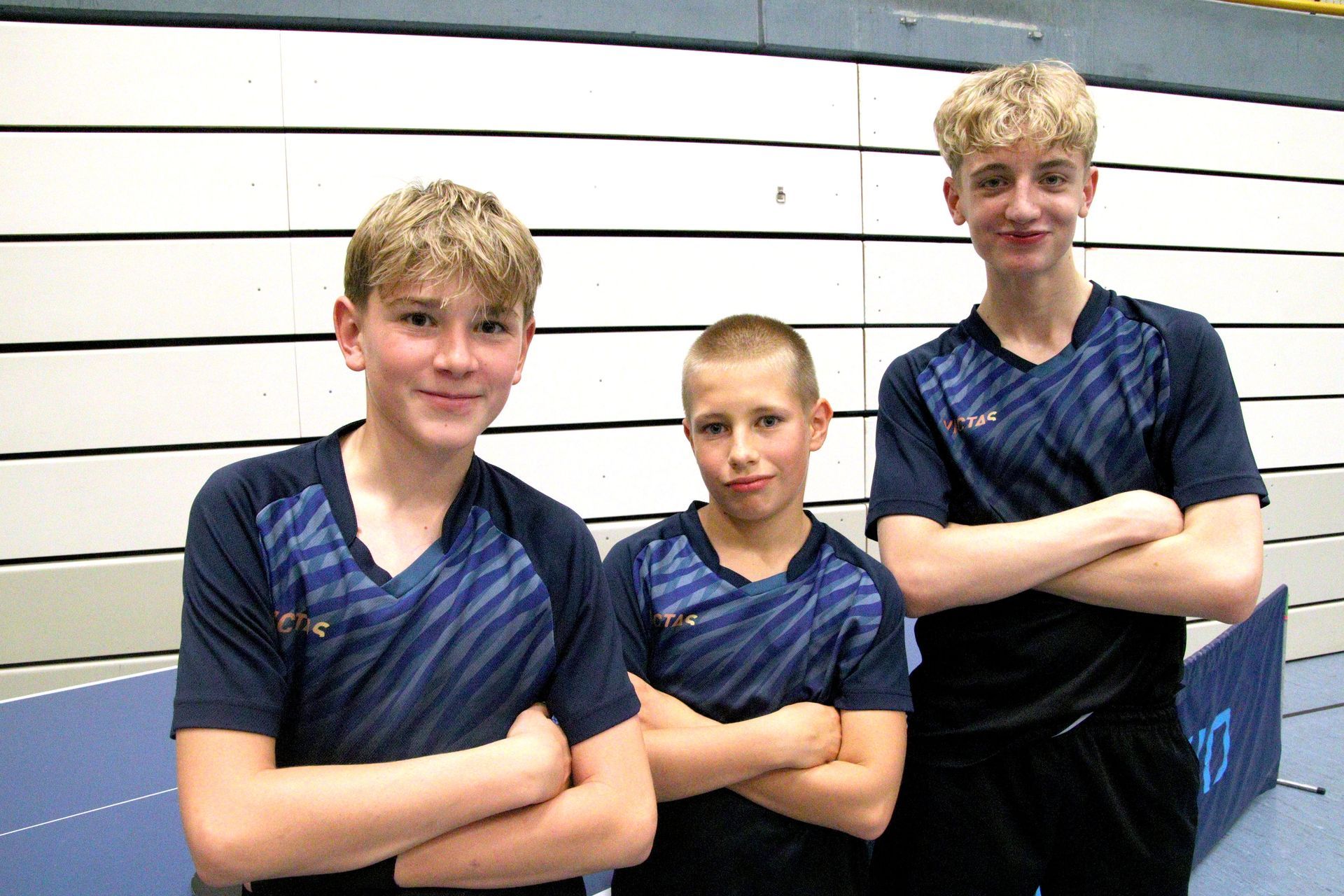 Eine Gruppe von jungen Jungen steht um einen Pingpong-Tisch herum