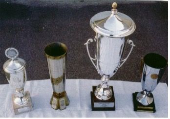 Vier silberne Trophäen stehen aufgereiht auf einem Tisch