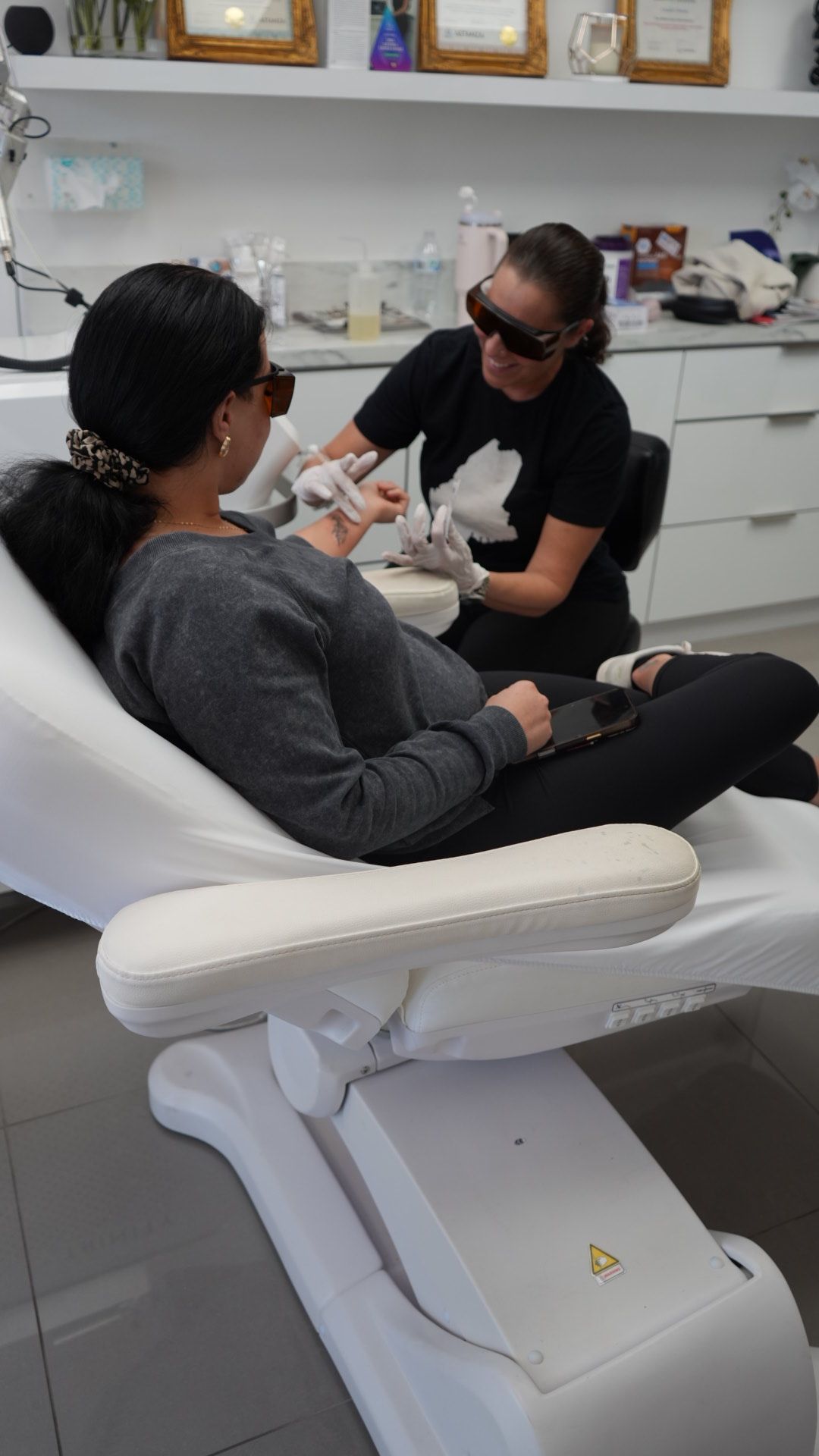 A person receiving laser treatment on their hand in a clinic. Another person is operating the laser.