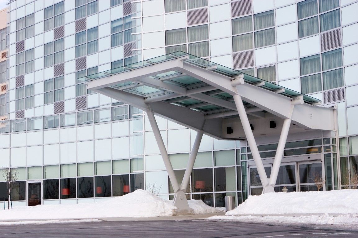 Modern glass building entrance with a white canopy and snow on the ground