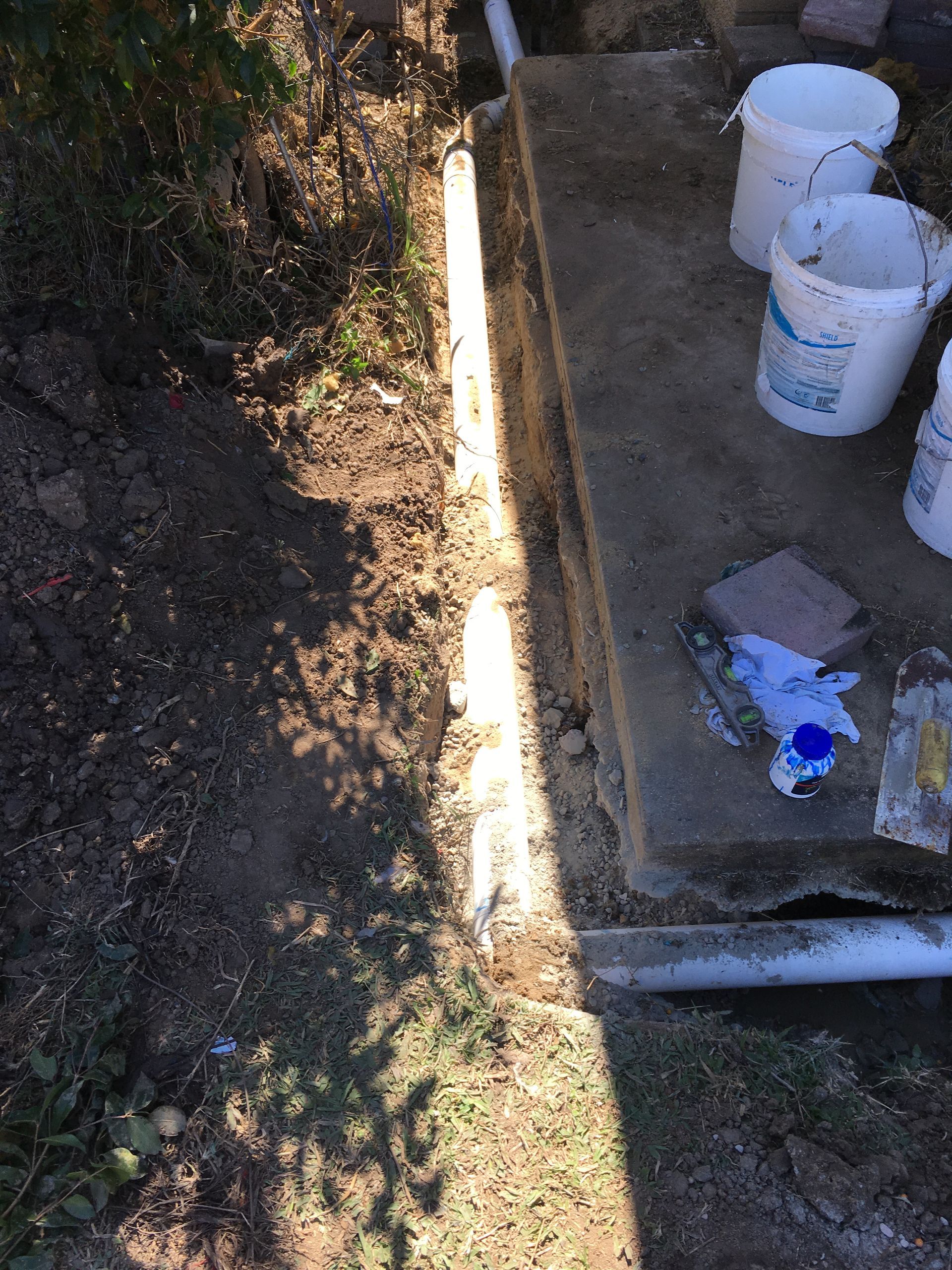 Concrete steps beside a dirt trench, with white buckets and a blue glove on the landing. — Depinto Agencies In North Mackay, QLD