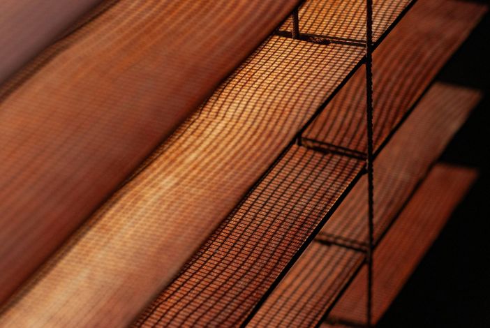 Close-up of wooden blinds with warm orange light filtering through the slats
