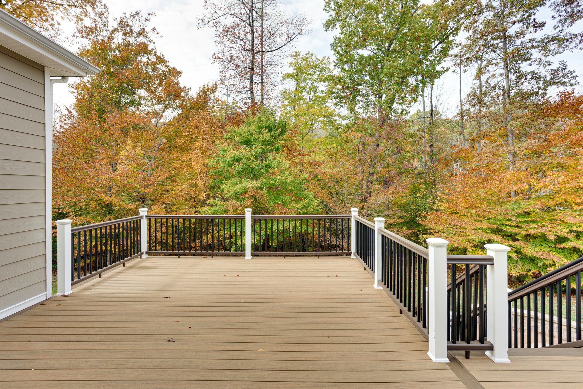 There is a large deck with a railing and stairs leading up to it.